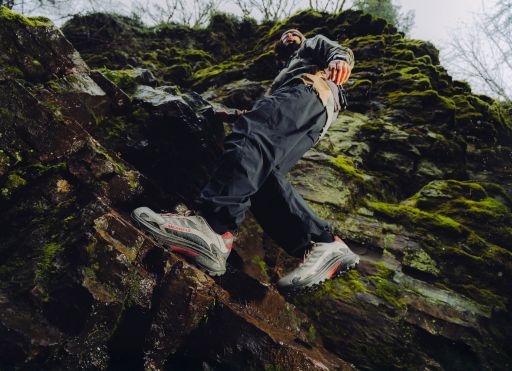 Man climbing mossy rocks wearing Merrell Moab Speed 2 hiking shoes